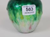 a green vase with a gold rim on a white surface