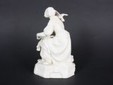 white statue of a woman sitting on a rock with a bird in her hand