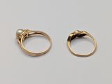 two gold rings with pearls on them sitting on top of a table