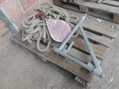 une palette en bois sur laquelle sont posés une corde et un objet métallique