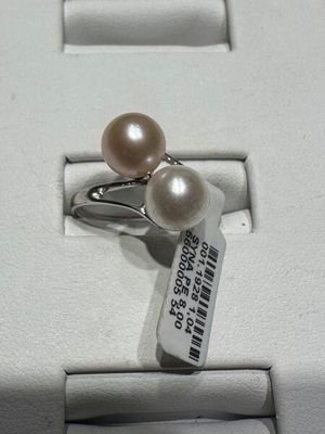 une bague ornée de deux perles, exposée dans une vitrine