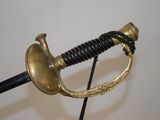 a gold colored sword with a black handle on a black stand
