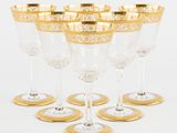 six verres à vin à bord doré sont alignés en rangée