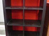 une bibliothèque noire aux étagères rouges dans une pièce dont l'un des murs est rouge