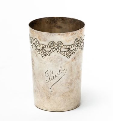 an old silver cup with writing on it sitting on a white surface