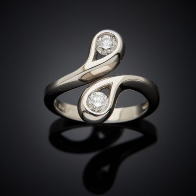 a close up of a ring with two diamonds on a black surface