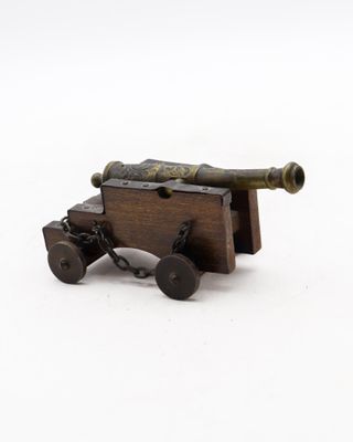 a small wooden cannon on wheels on a white surface