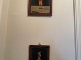 two paintings hanging on the wall above a toilet