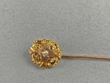 a close up of a gold pin with a flower on it