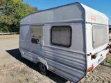 a small white trailer parked in a dirt lot