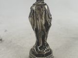 an antique silver figurine of a woman on a pedestal