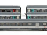 three silver train cars sitting next to each other on a white surface