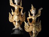 deux statues en or représentant une femme et un homme, posées sur un socle