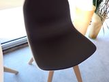 une chaise noire placée devant une fenêtre, avec une plante dans un coin
