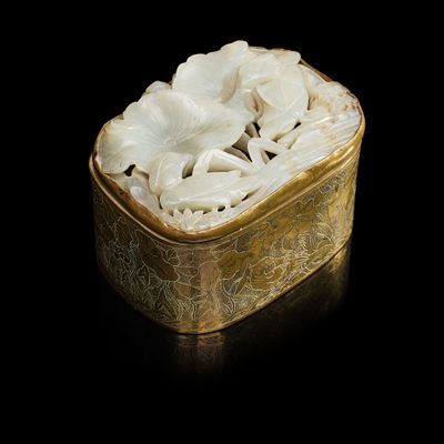 une boîte dorée contenant des fleurs blanches, posée sur un fond noir