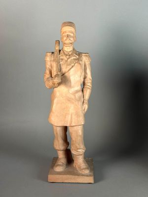 statue of a man with a rifle and a hat on a gray background