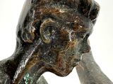 a bronze statue of a woman holding her hand to her face