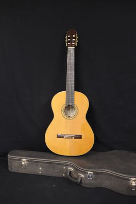 une guitare acoustique posée sur un étui à guitare, sur fond noir