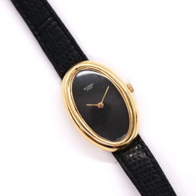 a close up of a watch on a black strap on a white surface