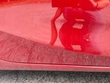 a woman taking a picture of herself in the reflection of a red car