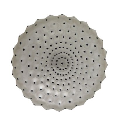 un bol blanc parsemé de points noirs, posé sur une surface blanche