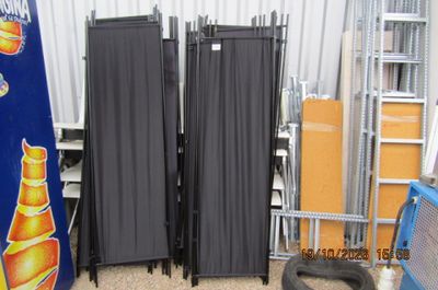 quatre chaises pliantes noires dans une pièce, adossées à un mur