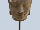 sculpture of a head on a wooden stand with a light blue background