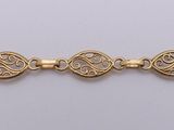 a close up of a gold plated bracelet on a white background