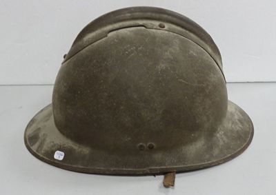 un vieux casque militaire est posé sur une surface blanche