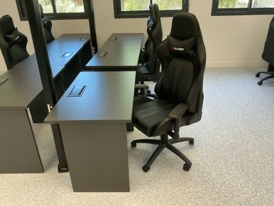 une photo d'un bureau vide avec des chaises et des bureaux noirs