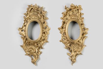 une paire de miroirs ovales dorés accrochés à un mur blanc, sur fond blanc