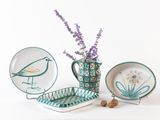 un vase avec des fleurs et une assiette sur laquelle est représenté un oiseau