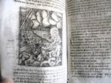 une main tenant un livre ouvert sur lequel figure l'image d'un homme dans un bateau
