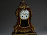 une horloge rouge et dorée surmontée d'un oiseau