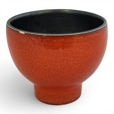 a red bowl with a black rim sitting on a white surface