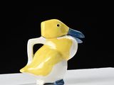 a yellow and white duck figurine sitting on a white table