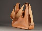 brown leather bag with strap and shoulder strap on grey background