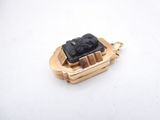 an image of a gold and black stone pendant on a white surface