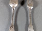 two silver spoons and a fork on a table