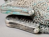 a silver purse with a chain around it on a table