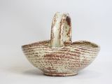 a white and brown bowl with a handle on it