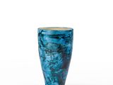 un vase bleu posé sur une surface blanche