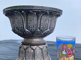 un vase en argent posé à côté d'un verre sur une table