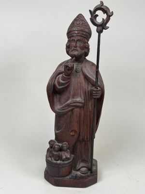a wooden statue of a man holding a staff and a bird