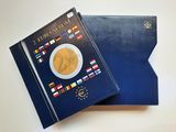 un classeur bleu sur lequel sont posés une pièce de monnaie et un livre