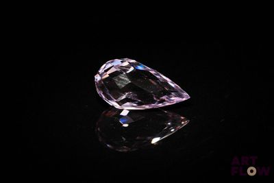 a close up of a pink diamond on a black surface
