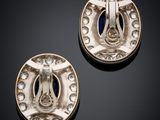 two silver and blue enamel buttons on a black surface