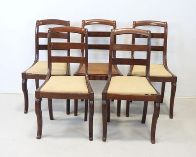 four wooden chairs with beige upholstered seats in front of a white wall