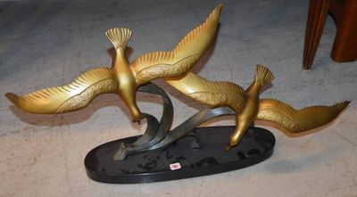 une statue représentant deux oiseaux, posée sur un socle au sol