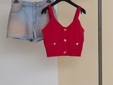 un ensemble composé d'un crop top rouge et d'un short en jean suspendu à un porte-vêtements